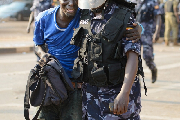 15/02/2016, A young man is helped by a policeman after being shot with a teargas canister during a demonstration in Wandegeya. Supporters of the Forum for Democratic Change (FDC) rioted after police had blocked Kizza Besigye from accessing Makerere University where he was meant to hold a campaign. This photo won The Uganda Press Photo Award (UPPA) 1st place in the news Category that year. © Jjumba Martin 2016.