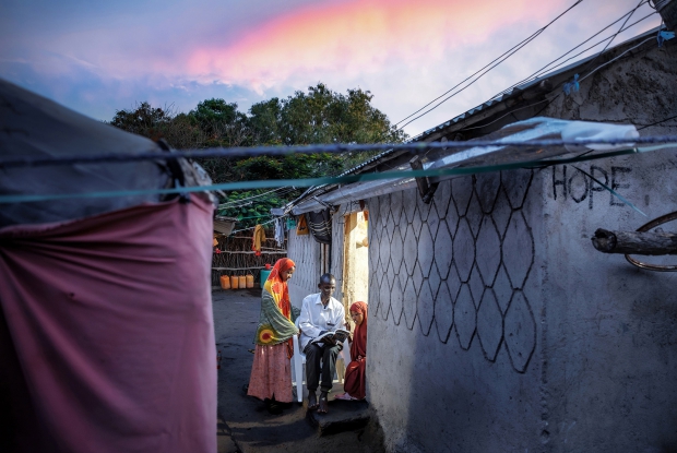 11.05.2024, Sheder refugee camp, Northeastern Fafan Zone in the Somali region of Ethiopia. - 58-year-old Muse takes two of his daughters through a school exercise with the use of light from the inside of one of the rooms in his compound.  The family of 14 has lived in the Sheder refugee camp for 10 years now, after fleeing AL Shabab in 2012.  &copy; MERCYCORPS/ Jjumba Martin 2024.