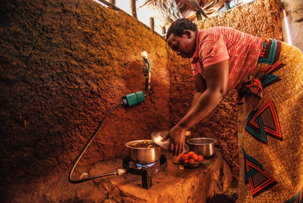 Luziwe prepares lunch for her children. She speaks with disbelief as she recounts the transformation in her family's life, emphasizing the newfound ability to cook for her children three meals daily, a simple pleasure that was once out of reach. &copy; CARE / Jjumba Martin 2024.
