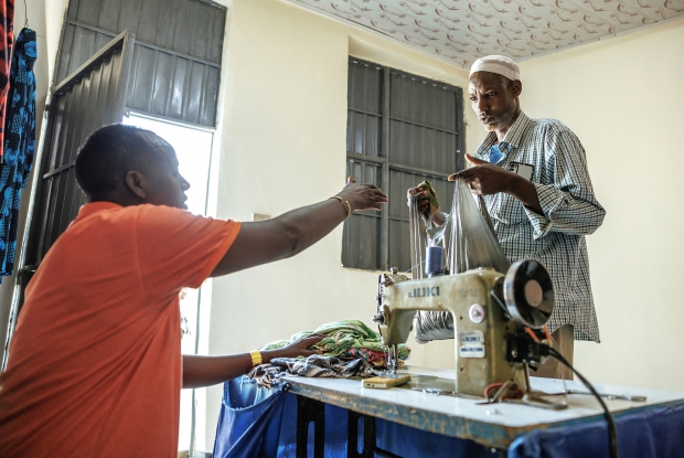 35-year-old Iiyas Hashi attends to a client at his tailoring shop at the business hub in Sheder town. &ldquo;This refugee camp is home to me and my six-member family. Tailoring is my source of income and I can assure you that business is going well, contrary to the years before. Before the introduction of the Mercy Corps' Enter Energy Project, I had no confidence to say so. Life in general and my ability to sustain the business were challenging. Because of the irregular electricity supply, I could only work for 3 hours out of the 12 work hours in the day. I was only earning peanuts so I couldn't even afford to provide my family's basic needs. This Mercy Corp project has made it possible for me to boost my productivity and generate more income. I also have a chance to expand my business with more services added to it. Very soon my income is going to increase. I'm going to be rich enough to take care of my family's needs.&rdquo;