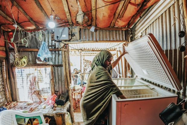 May 12th, 2024- Sheder Refugee Camp, Amina working at her shop in Sheder Refugee Camp. 33-year-old Amina Muhammad Hassan left Somalia on the 11th of November 2011 and they have been residents of the Seder camp since then with her family of 8 members. For the first time in a while, she lived in a place without conflict. However, she felt limited with movement as a refugee in Ethiopia. The other thing was how hard it was to manage the family with no financial security. To the list of challenges she faced in the refugee camp, Amina adds that for years, she and the other refugees struggled with the lack of a constant supply of electricity. &ldquo;Most of the time, I couldn't run my businesses due to the limited power supply. As a person who runs a fruit juice and grilled meat business, I needed a constant supply of electricity, if I was to record any form of business growth.&rdquo; Amina is happy for the Mercy Corps' Enter Energy Project because her business no longer has electricity challenges and, therefore makes more money. Back at home, we no longer live in the dark and my children can do homework at night. I can even charge my phone whenever necessary without having to travel to the trading center. Now, there is a fully functional hair salon in my neighborhood. On a personal level, Amina confirms that her dream of creating assets that her children can inherit has started taking shape. At her shop, Amina has a refrigerator, which stores fresh smoothies and cold water that are essential in a hot place like Sheder. The Enter Energy Program aims to improve the climate resilience of displaced populations by harnessing the power of public and private capital to deploy sustainable energy-as-a-service solutions to displaced populations, their host communities, and the humanitarian actors that support them; as well as empowering livelihoods through the productive use of energy. Humanitarian Energy aims to scale this model to 10 of the most crisis-affected countries in the next 10 years.