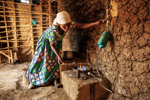 Nyirazibera prepares a meal using biogas. She is one of the women  who used to spend hours collecting firewood. Her family is a beneficiary of CARE's biodigester program and she  joyfully shares that the once-dreaded two-hour journey to Bugoma forest, to fetch firewood is now a thing of the past.  &copy; CARE / Jjumba Martin 2024.
