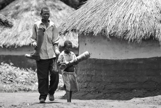 2015, Pader district, Northern Uganda. Ocitti Ceaser with his son, carry prosthetic legs for repair. Ceaser is a Land mine survivor who lost both his legs during the Kony war and had a bilateral below-knee amputation. These prosthetics must be replaced every 2-3 years for adults due to general wear and tear breakages and rigorous activities like farming. &copy; Jjumba Martin, AVSI Foundation 2015