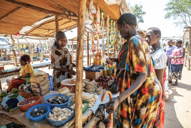 07/06/2024, Bidibidi Refugee settlement, Uganda. Rahima at her grocery stall in a local market. Upon her arrival at the camp, Rahima, a Single mother of five children relied on humanitarian relief assistance provided by the World Food Program and UN Agencies in the camp and it was hard for her to provide all the family basics. The DREAMS program provided Rahima with a seed grant, enabling her to start a business retailing mixed goods.  Whenever Rahima has a minute to spare, she makes/designs bedsheets for sale. Her current business value is worth about 1.6 million Uganda shillings. These enterprises enabled her to support her children by paying their school requirements, medical bills, clothing, and food.