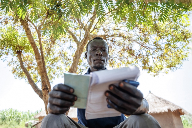 October 4th, 2022-, Bidibidi Refugee settlement, Uganda. 30-year-old Festo, the Vice chairperson of Ala-Zabu savings group, attends one of the group meetings. Under the DREAMS program, a consortium of Mercy Corps, Village Enterprise and IDinsight, support has been extended to the savings group comprising refugees from South Sudan to work together, save money, start businesses, to become self-reliant. Here, the members of the savings group have gathered to save money and review their goals. The members have been trained by business mentors from Village Enterprise in financial literacy, budgeting and record keeping.