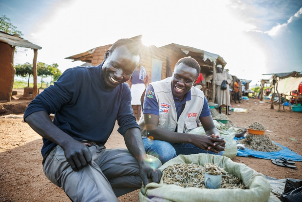 October 4th, 2022-Bidibidi Refugee settlement, Uganda. Sanya, the Project Officer, Mercy Corps in Yumbe district, interacts with Festo, a South Sudanese refugee and beneficiary of the DREAMS Program. James with his two colleagues have set up this business in the local market where they sell silver fish, a popular and high-nutrient dish among the people here.