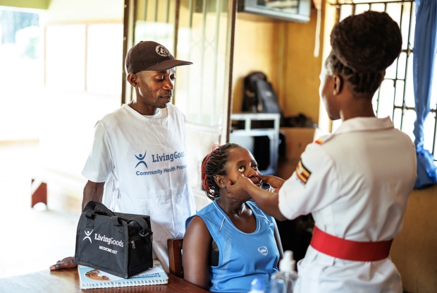 Namirembe Leah, the Assistant Nursing Officer of Kasekulo Health Centre ii, examines Mable Muwanguzia at the health facility while Kiriibwa Ronald, the community health worker, looks on. Living Goods fosters partnerships between government health facilities and Community health workers to ensure smooth service delivery.