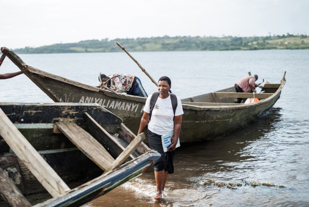 Nantumbwe Josephine disembarks off a boat on her way back from Kalangala Health Centre iii. Josephine is the Lwabaswa village community health worker whose work occasionally compels her to accompany her patients to the health facility to foster her working relationship with the health team at the Government facility.