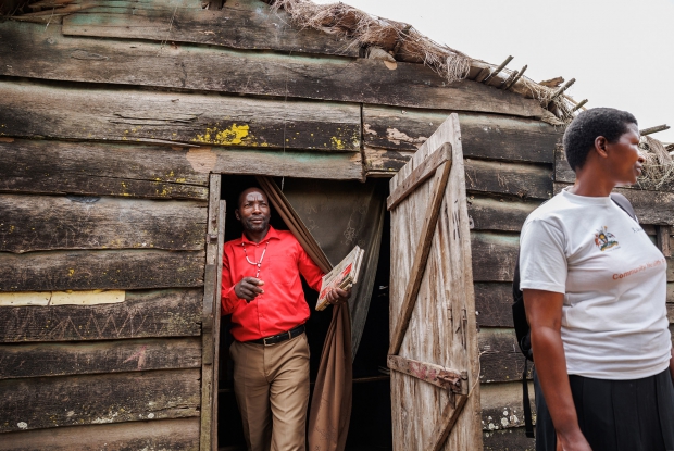 Mugisha Richard, 42, the Local Council Chairperson of the Lwabaswa-Buvuma landing site and fishing village in Kalangala District, speaks through the public address system inside a makeshift private cinema hall.  These cinemas have loud speakers that can broadcast sound to the whole landing site and inform them about different health programs in the community.  Richard offers communication and mobilization support to Nantumbwe Judith, the Community Health Worker.