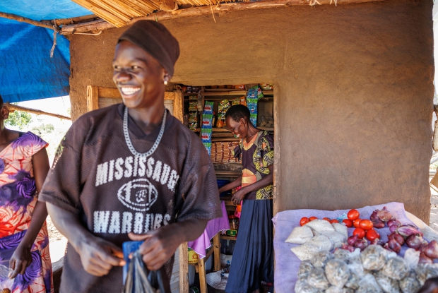 October 6th 2022- Yumbe district- Uganda. Village 1A, zone 4 Bidi bidi refugee settlement. - Juan Betty, one third of the Saidu Business Group attends to a customer. Juan fled South Sudan in October 2016 and sought refuge in Uganda. She says the DREAMS Program has enabled her to provide for her family to an extent  and together with her two colleagues, grow the business further.